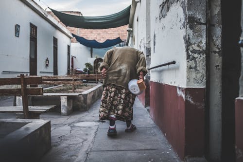 Old Person Walking Near Concrete Building