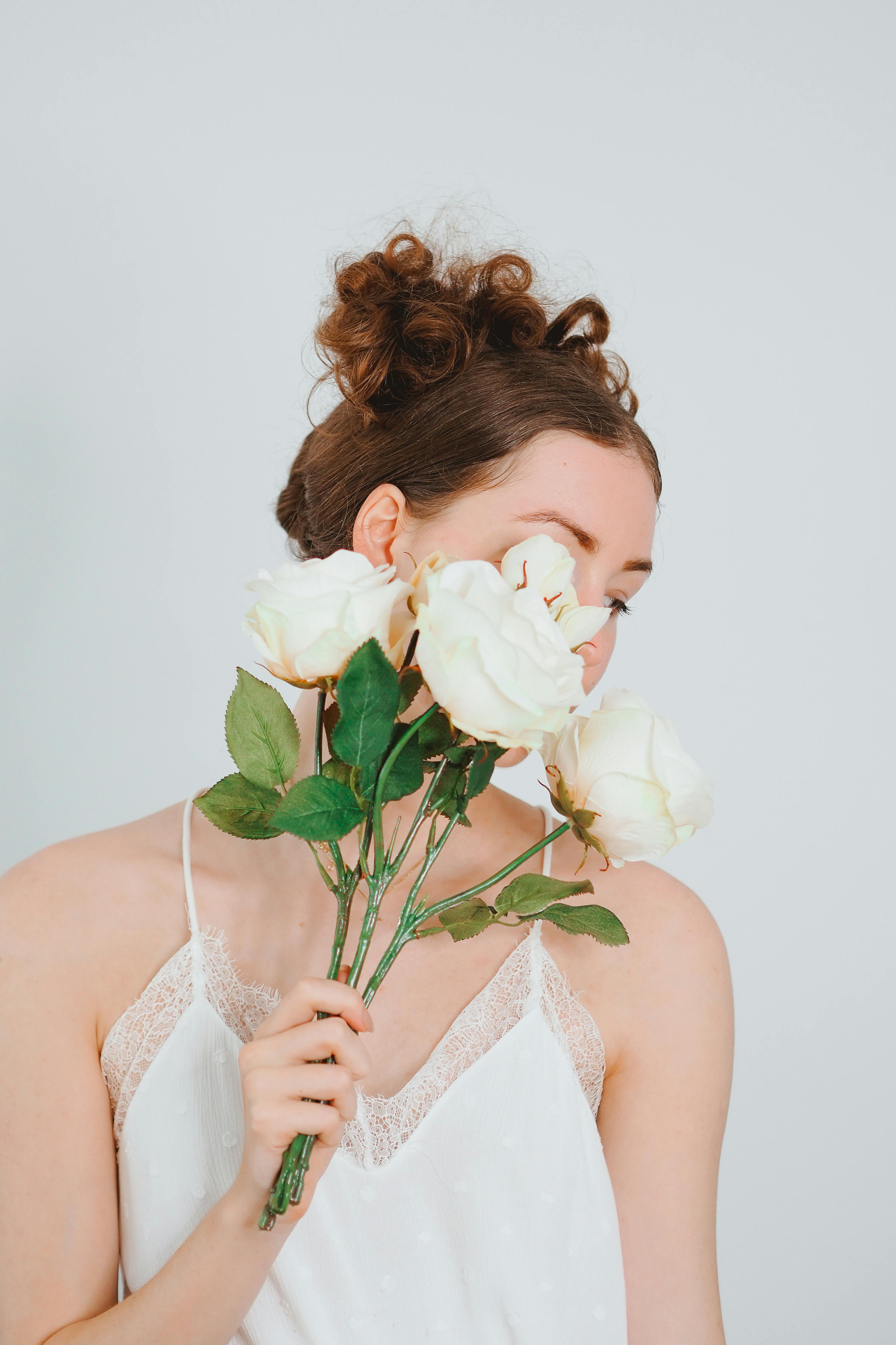 A young woman in a white blouse poses with white roses in a Paris studio setting.