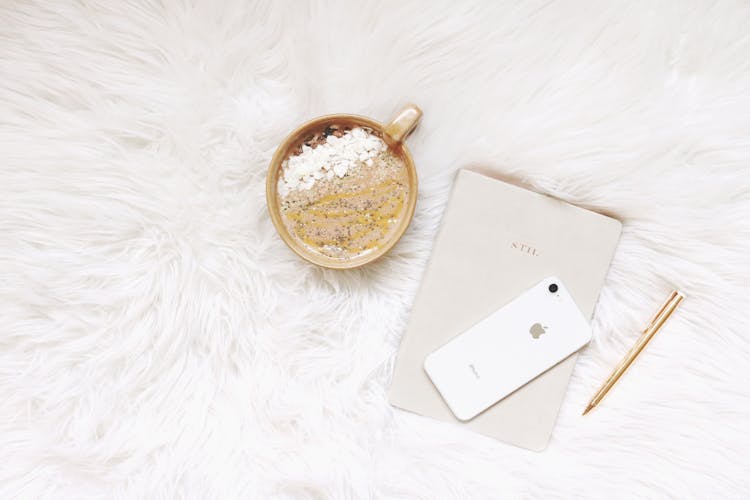 White Iphone, Gold-colored Pen, And Round Gold-colored Cup