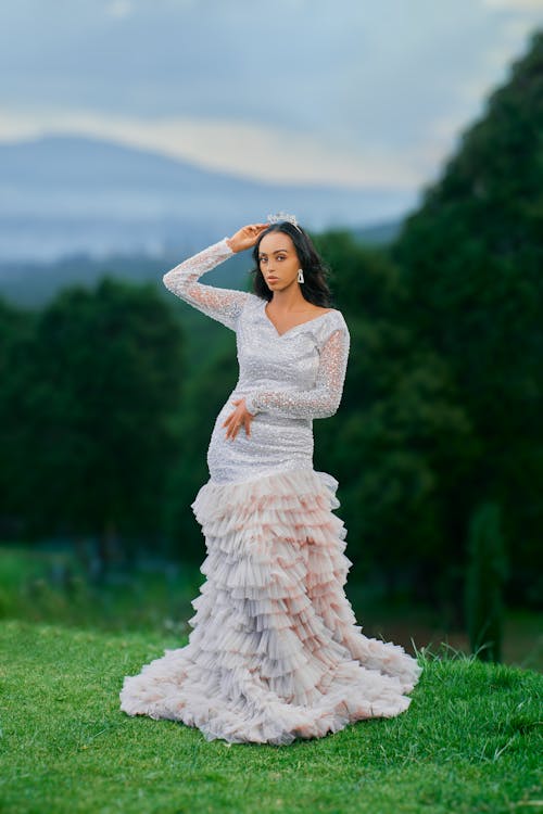 A beautiful woman in a wedding dress poses on a hill