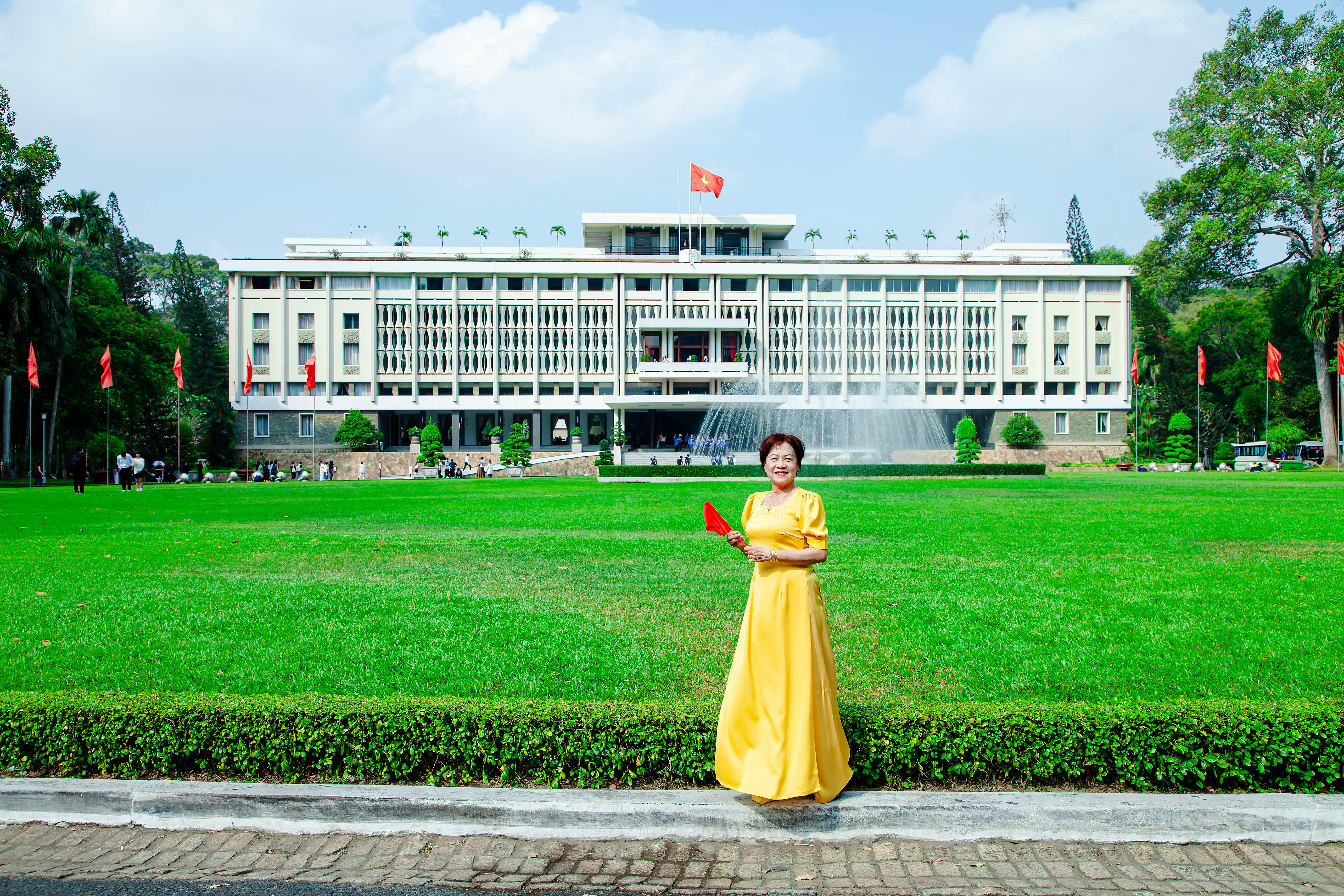 A woman in a yellow dress stands in front of a building