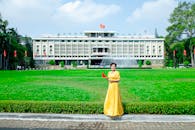 Woman in Yellow Dress Standing with Independence Palace in Ho Chi Minh behind