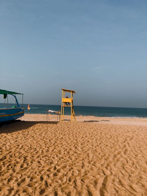 Free A peaceful view of a Goan beach with a lifeguard tower and boat under clear skies. Stock Photo