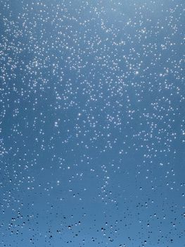 Abstract view of raindrops on a glass window shining under daylight.