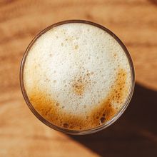 Dense creamy foam cap on a tall glass seen from above, photo by Jakub Zerdzicki on Pexels