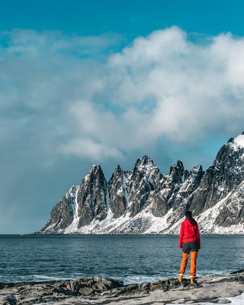 Person Standing on Gray Rock Near Body of Water