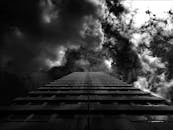 黑白照片中，一座高耸的建筑头顶着戏剧性的云层，营造出喜怒无常而引人注目的城市场景