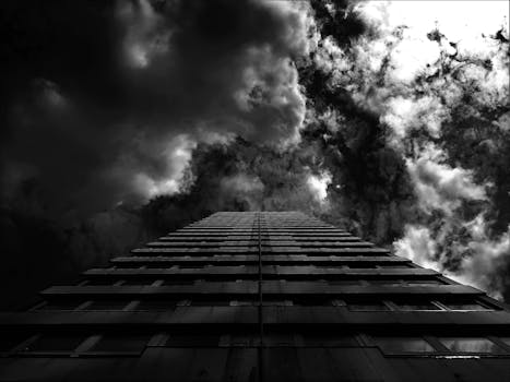 黑白照片中，一座高耸的建筑头顶着戏剧性的云层，营造出喜怒无常而引人注目的城市场景