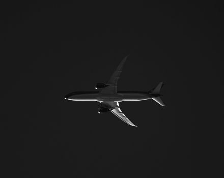A striking black and white silhouette showing an airplane soaring high in the sky.