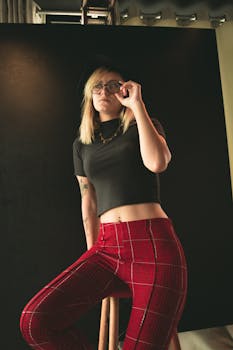 一位戴着眼镜、穿着时尚服装的女性在室内自信地摆着姿势