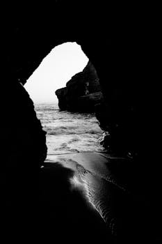 Black and white view of the sea through a cave, creating a dramatic silhouette.