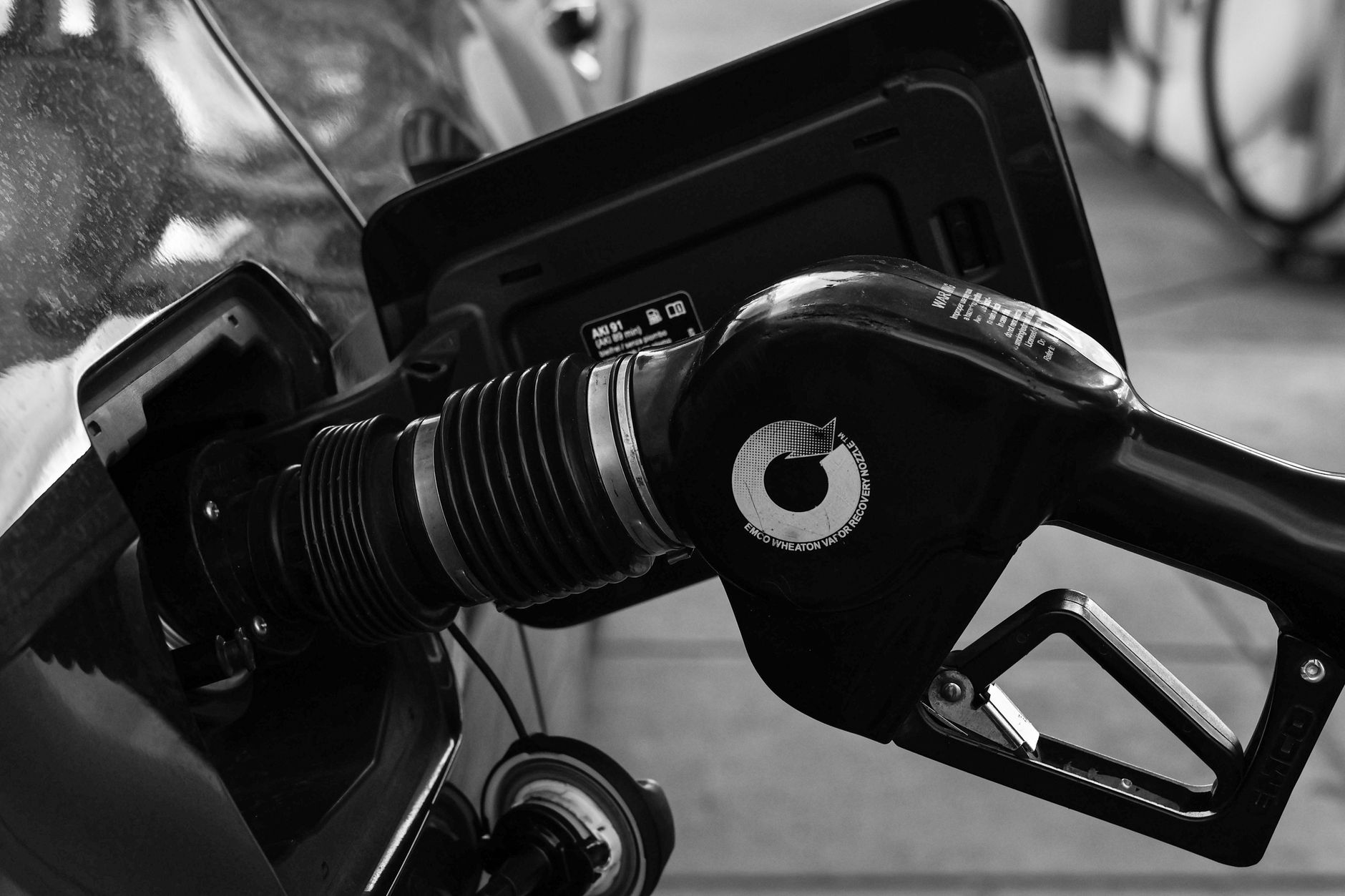 Detailed close-up of a refueling nozzle in monochrome at a gas station, highlighting the petrol filling process.