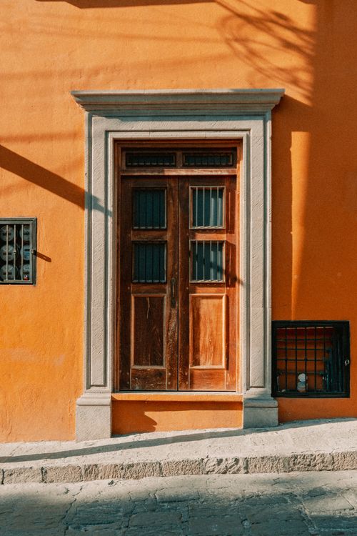 Free Classic wooden door on vibrant orange colonial facade in Guanajuato, Mexico, showcasing traditional architecture. Stock Photo