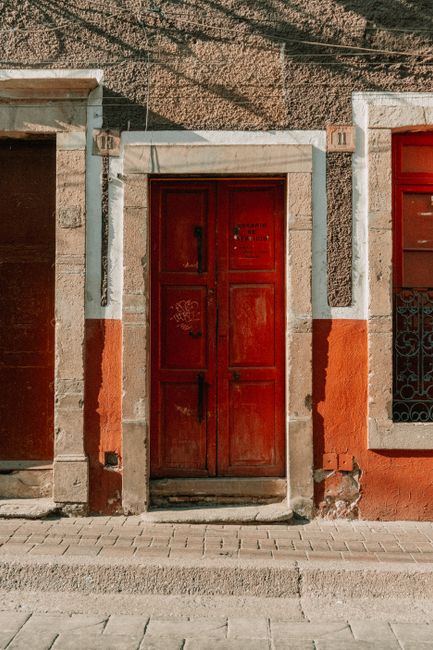 Rustic red door on a colorful façade in Guanajuato, Mexico, capturing local architecture.