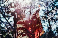 一位身着中国传统服装的女子，在盛开的樱花丛中优雅地与蝴蝶互动