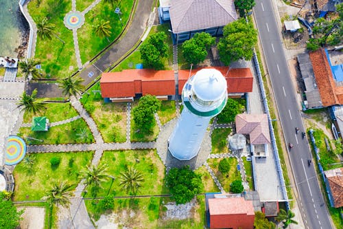 Fotografia Aérea Do Farol Branco Perto De Casas Multicoloridas E Vista Do Campo Verde