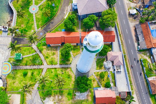 Vibrant aerial view of a lighthouse in Banten, Indonesia with surrounding greenery and architecture.