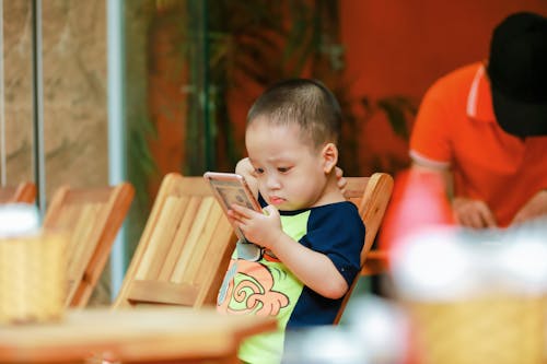 Free Selective Focus Photography of Toddler Holding Smartphone Stock Photo