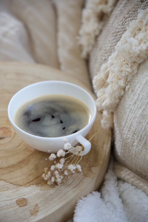 A cup of coffee on a wooden tray with a blanket