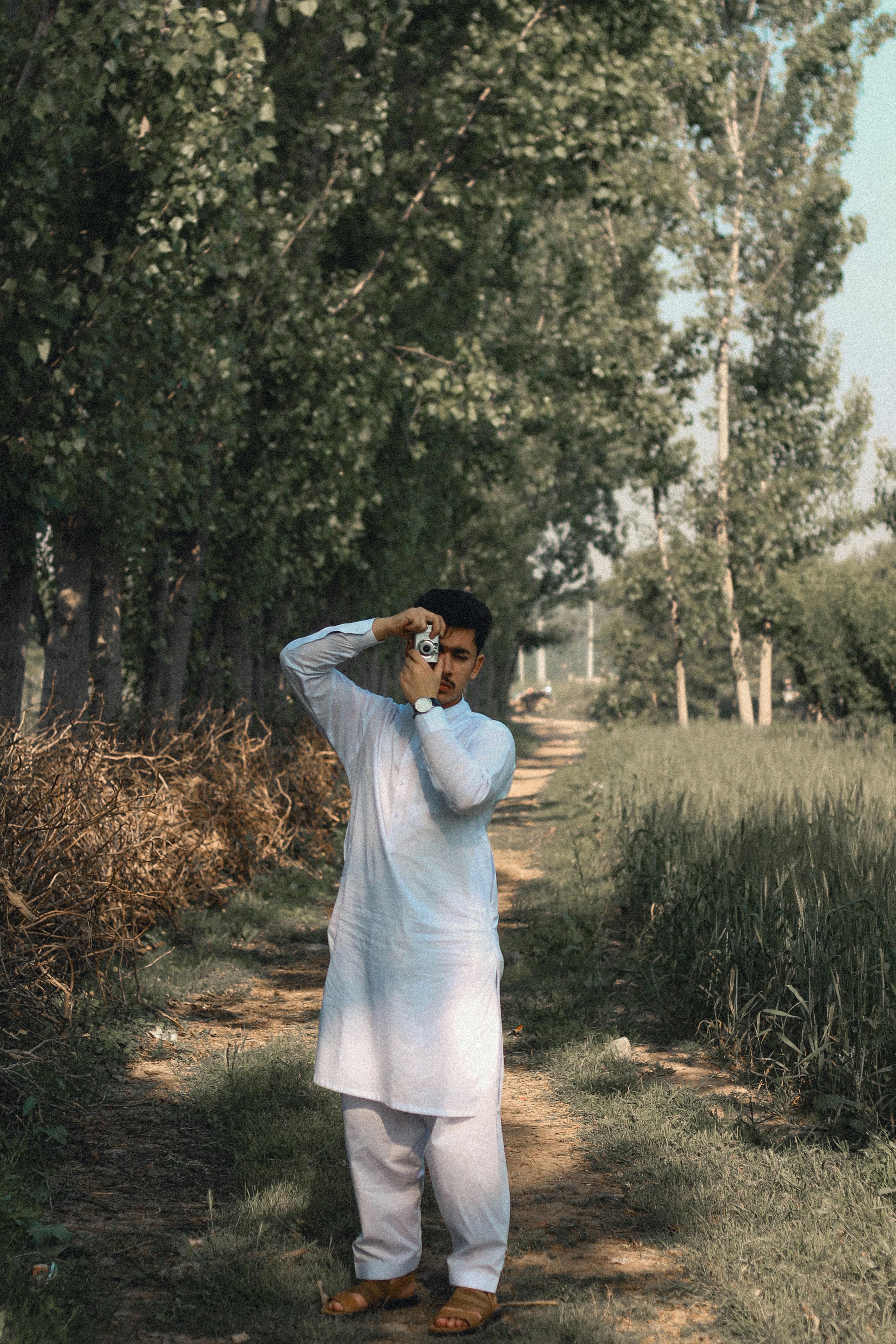 man dressed in white taking photos standing on a path