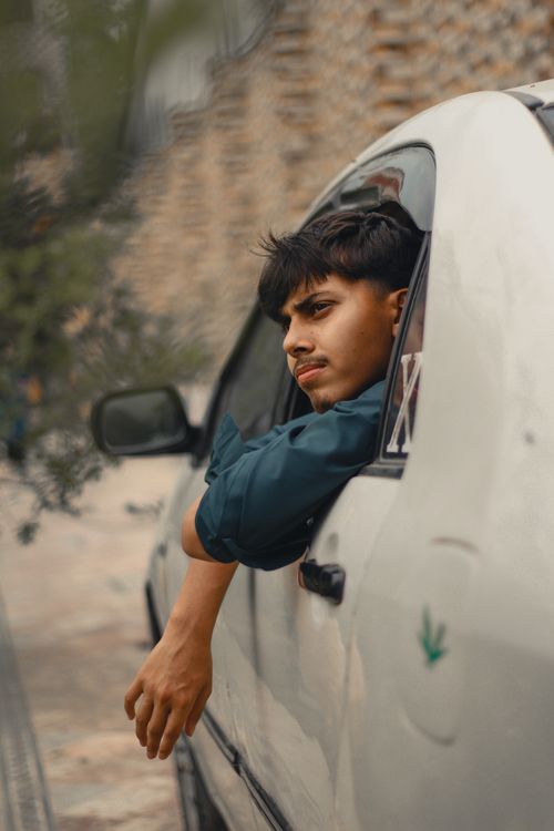 Free A young man with a mustache looks out from a car window in Peshawar, Pakistan. Stock Photo