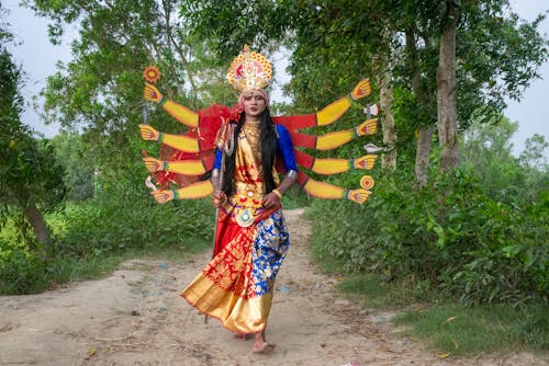 A woman dressed in traditional indian clothing is walking down a dirt road