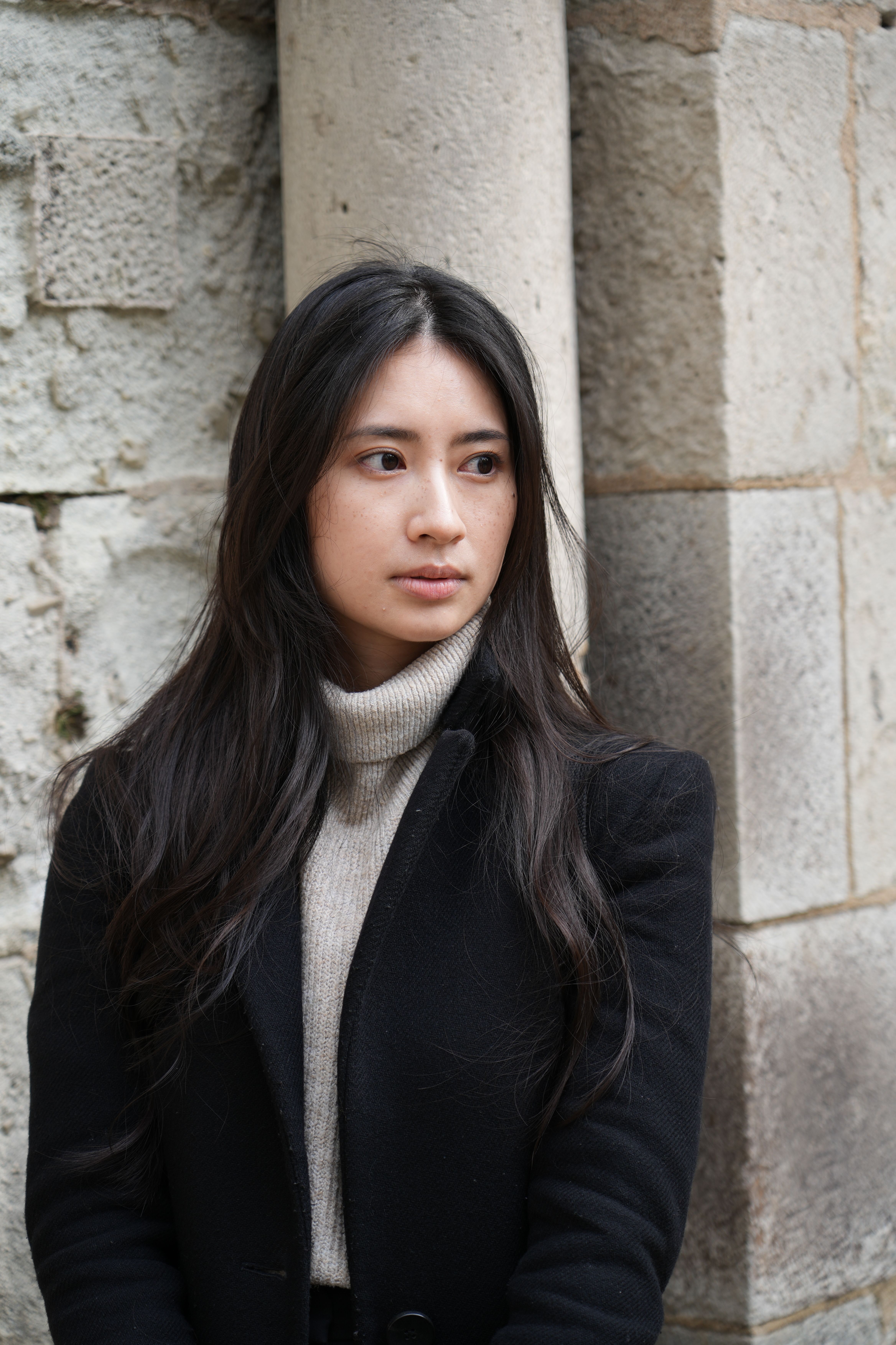 Portrait of a young woman posing outdoors in a black coat, Cologne, Germany.