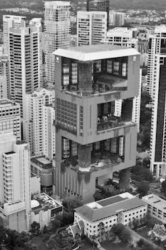 Black and white aerial view of unique Singapore skyscraper amidst cityscape.