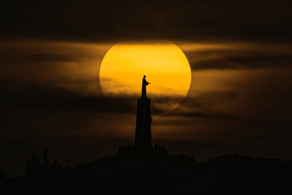 Silhouette of the Cerro de los Angeles statue against a dramatic sunset sky in Madrid, Spain.