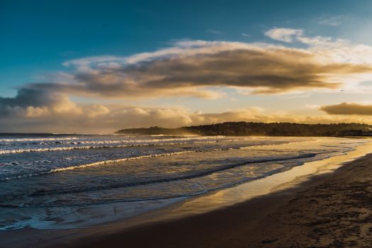 Idyllic beach landscape with golden sky and waves during sunset, perfect for peaceful scenery lovers.
