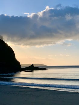 Peaceful sunrise over the sea at St Austell, England, with dramatic clouds and a serene coastline.
