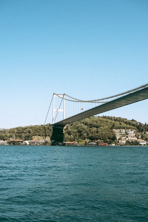 Free A scenic view of the Bosphorus Bridge spanning over calm blue waters with lush greenery in Istanbul. Stock Photo