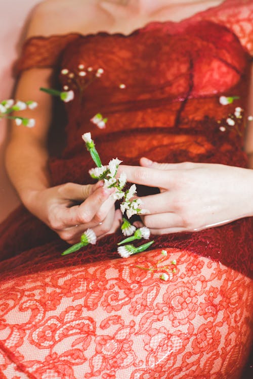 A woman in red lace dress holding flowers