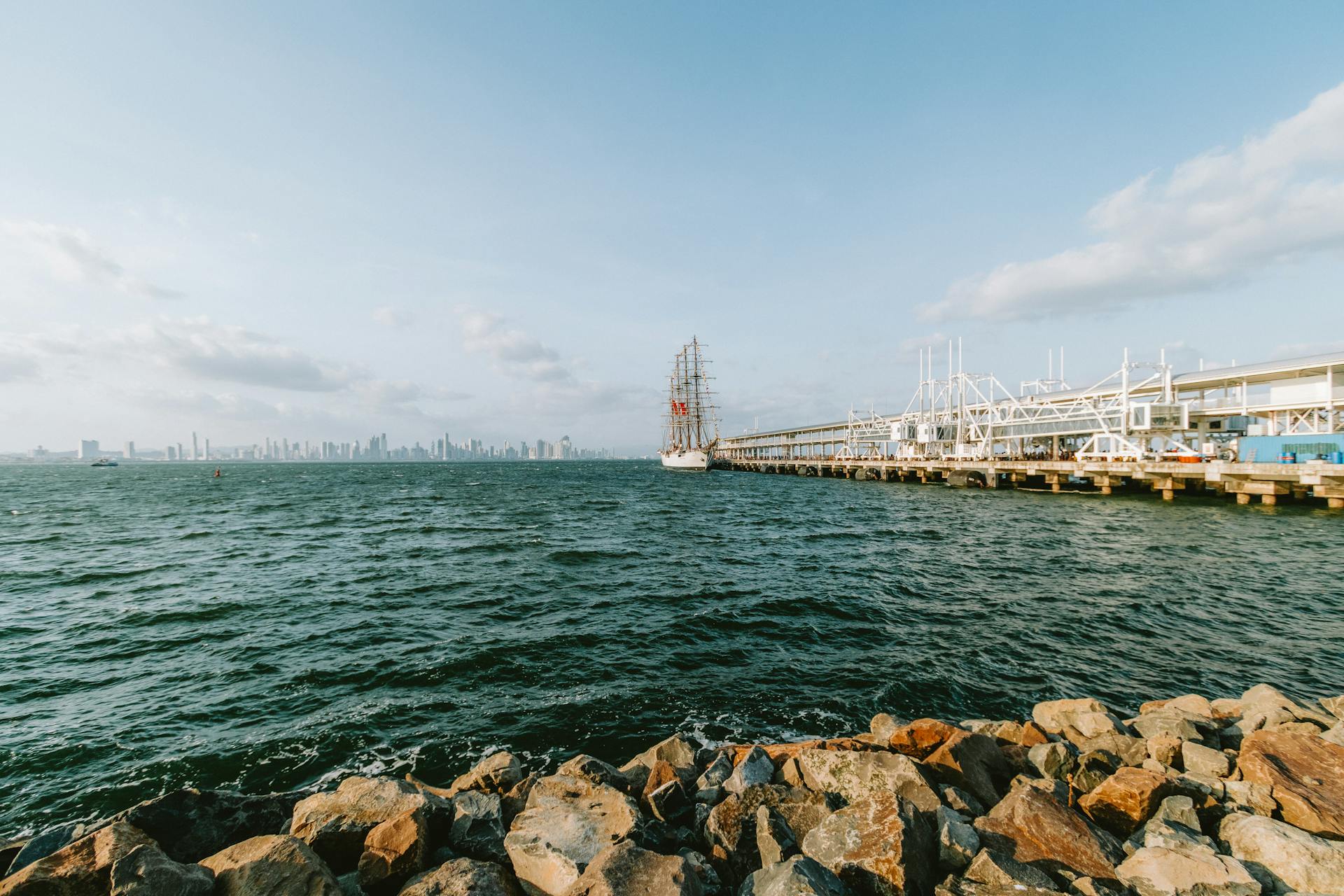 A picturesque view of the waterfront in Panama City with a ship docked at the pier and the skyline in the background.