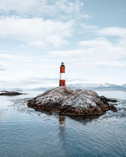 Stunning view of a classic lighthouse on a rocky island surrounded by calm ocean waters.