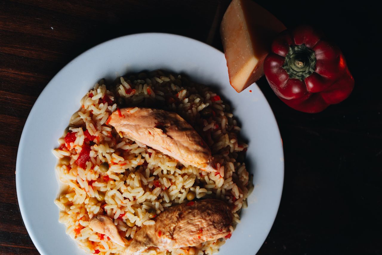 Top view of chicken and yellow rice dish with red bell pepper on a plate