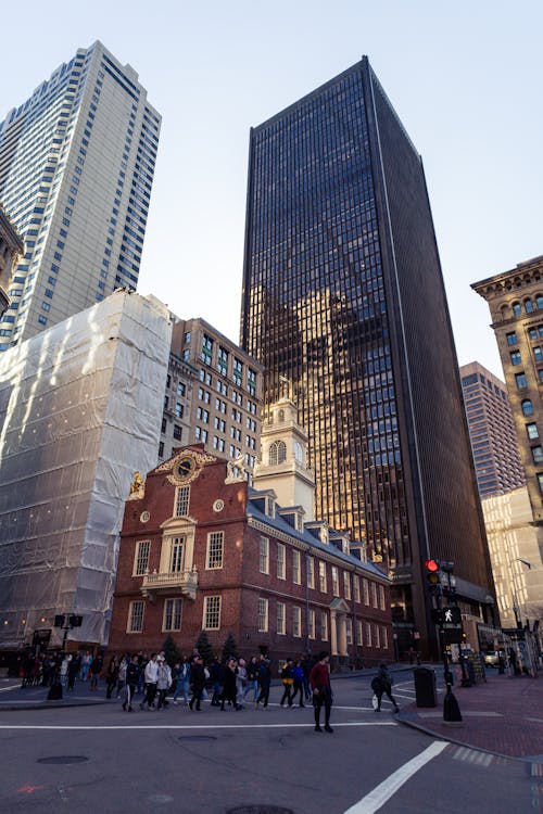 A group of people walking across a street in front of a tall building