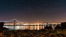 里斯本迷人的夜色中，明亮的吊桥上方是星空