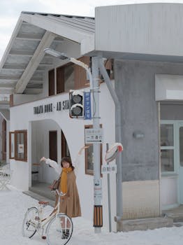 A joyful Asian woman poses with her bicycle in a snowy urban setting.