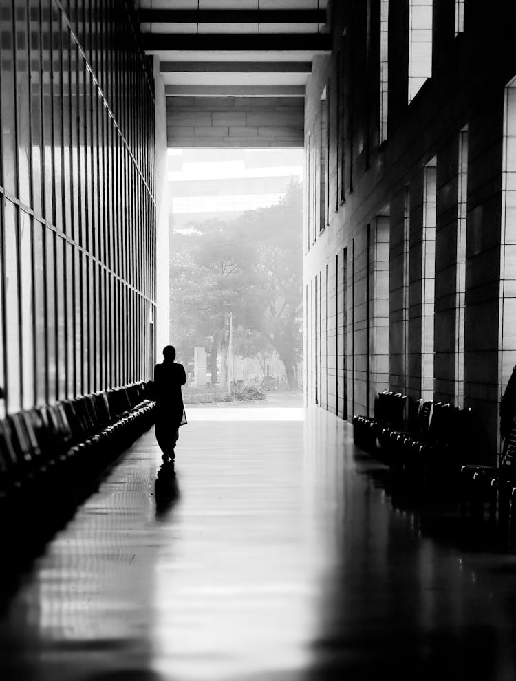 Silhouette Of A Person Waiting Between Rows Of Empty Seats