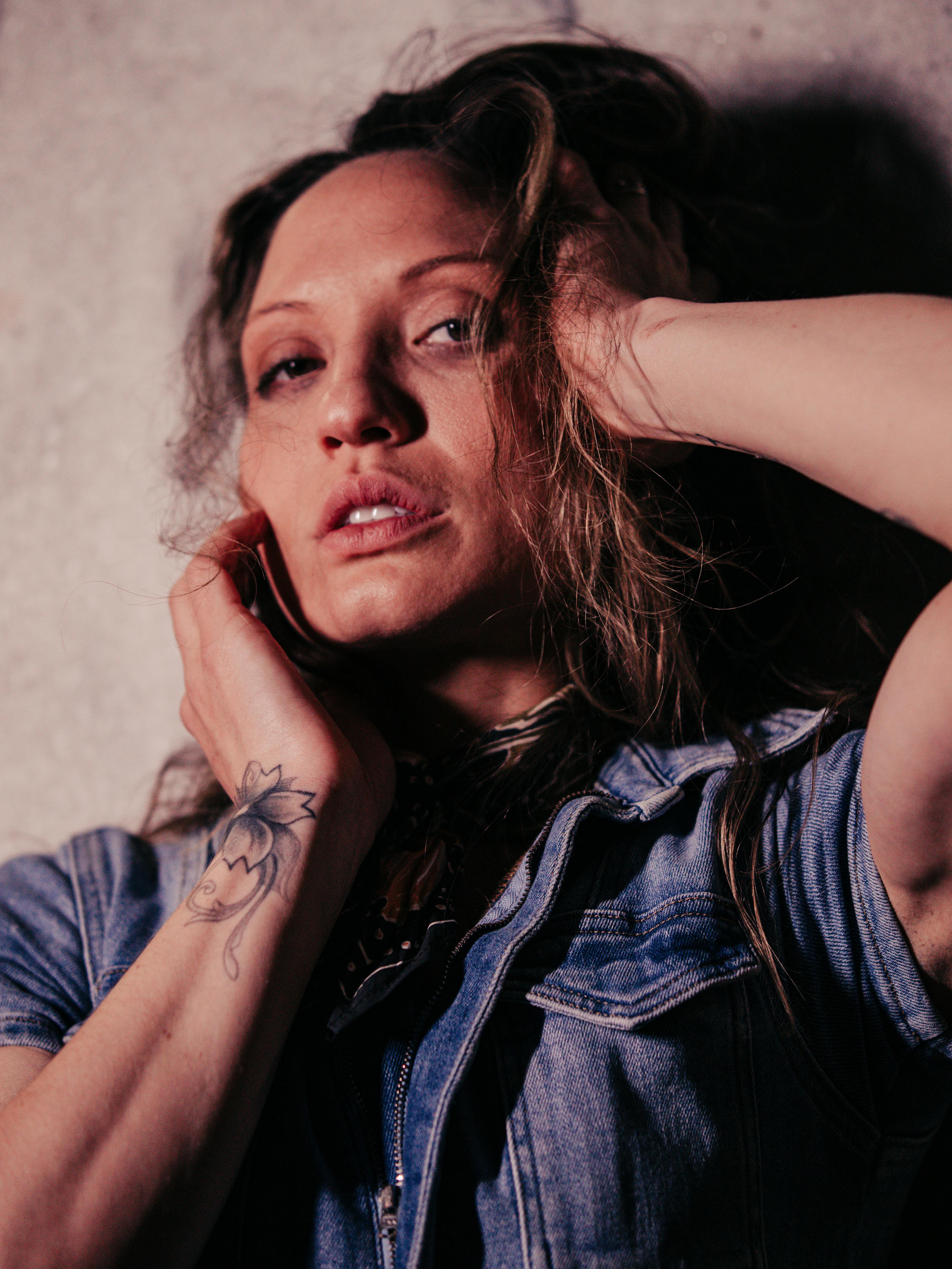 A stunning portrait of a tattooed woman in denim, exuding vintage elegance.