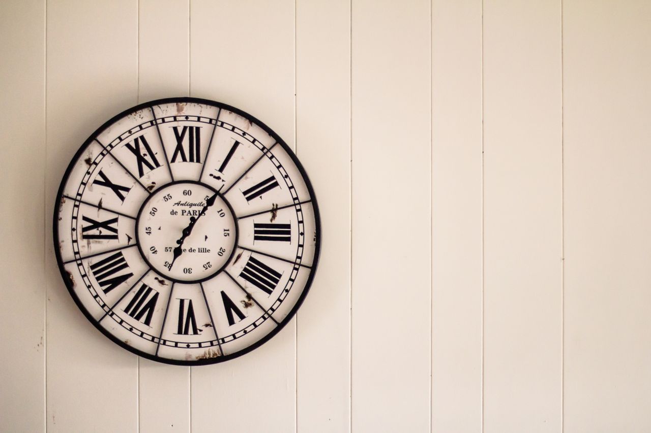 retro wall clock with roman numerals on a white wooden background