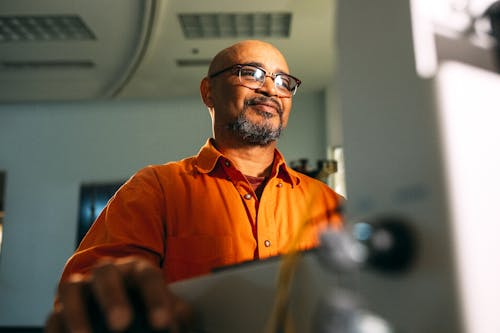 コンピューターに面した眼鏡をかけている男