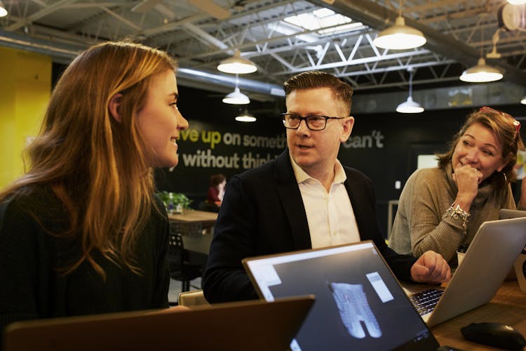 Man Talking In The Middle Of Two Women