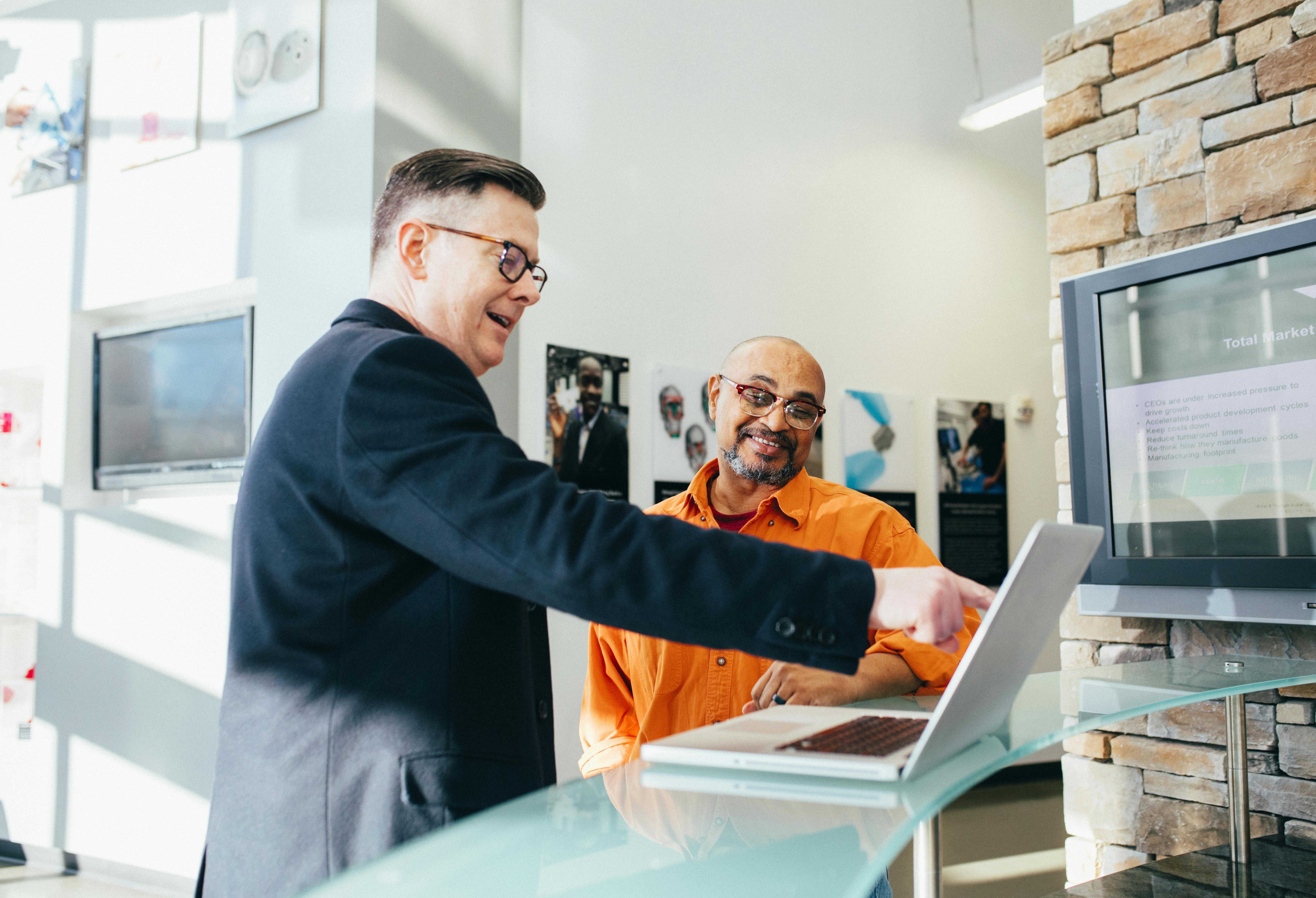 Business advisor showing loan options on a laptop to a contractor, helping him understand financing solutions for construction projects