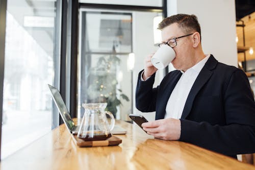 Free Man Drinking Coffee in Front of His Laptop Stock Photo