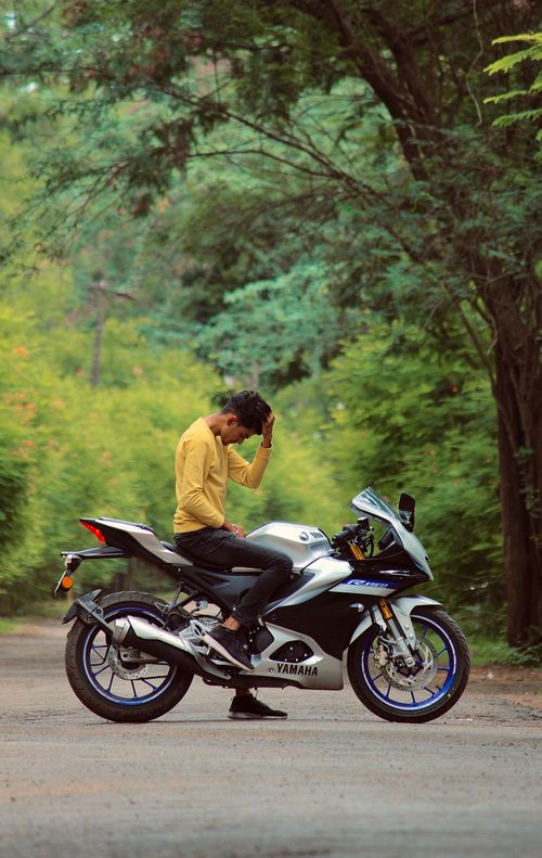 Free Man sitting on a sport bike along a lush green road in Salem, India during summer. Stock Photo
