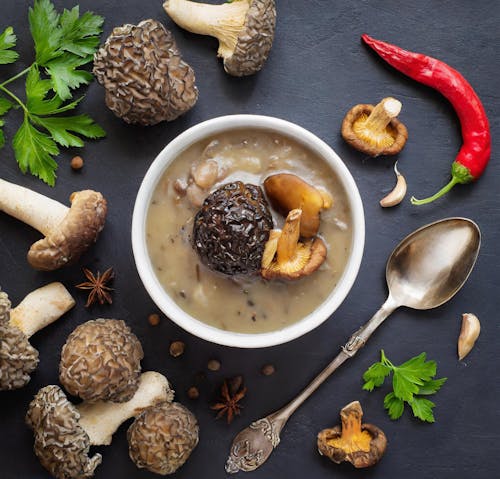 A bowl of soup with mushrooms, spices and herbs