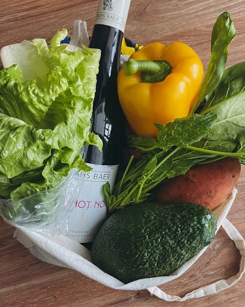 A bag with vegetables, wine and a bottle of wine