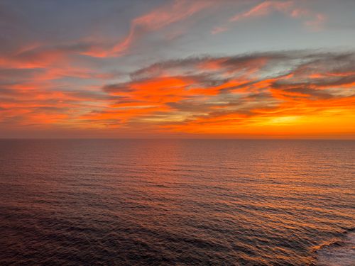 Free Beautiful ocean horizon at sunset with vivid orange clouds, perfect for tranquil nature scenes. Stock Photo